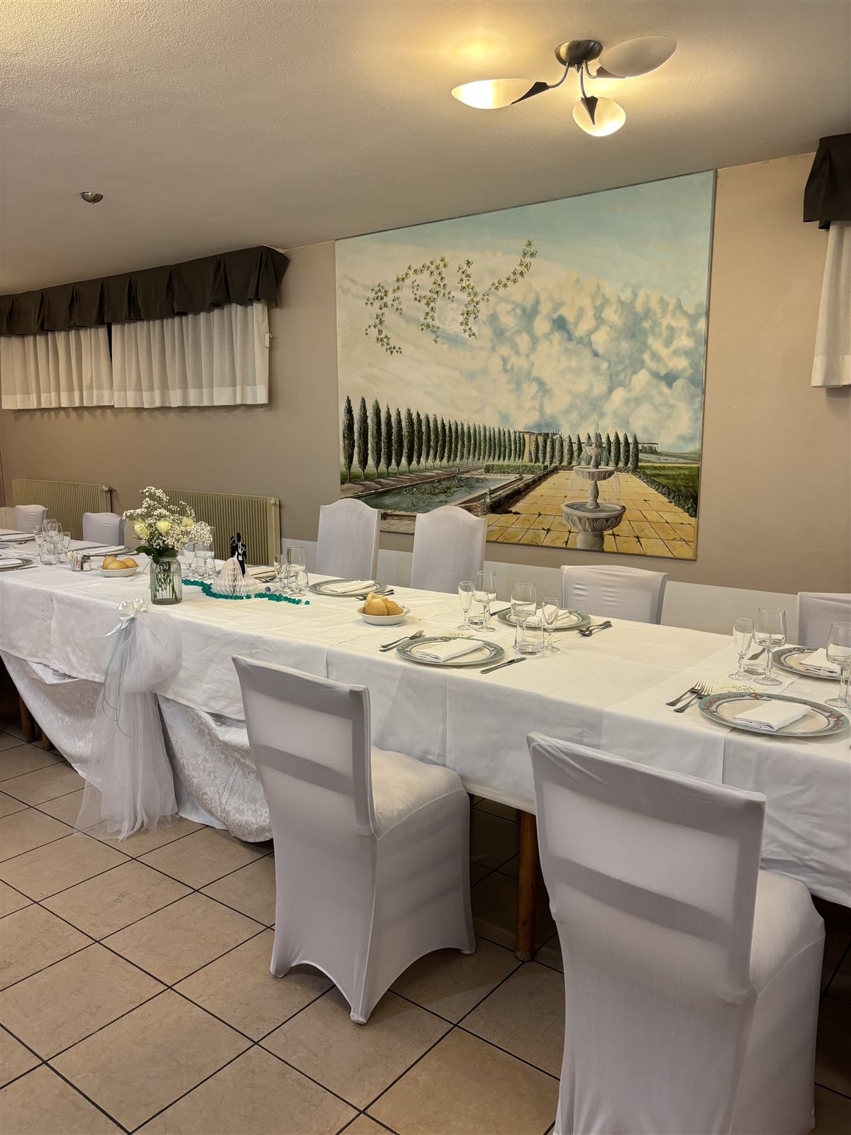 La sala elegante con tavoli vestiti di bianco e un grande dipinto alle pareti